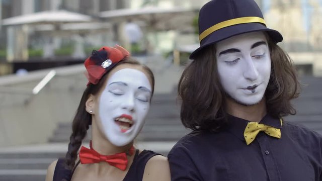 Girl and guy mimes play with hands