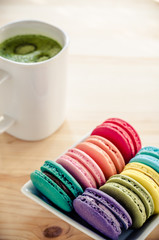 Colorful macaroons and green tea on wooden table background: vintage tone
