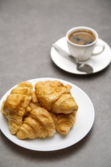 Cup of fresh coffee with croissants on dark background