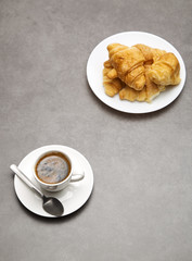 Cup of fresh coffee with croissants on dark background