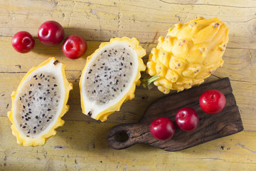 yellow pitahaya or dragon fruit and red plum on wooden background