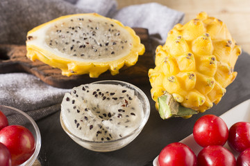 yellow pitahaya or dragon fruit and red plum on wooden background