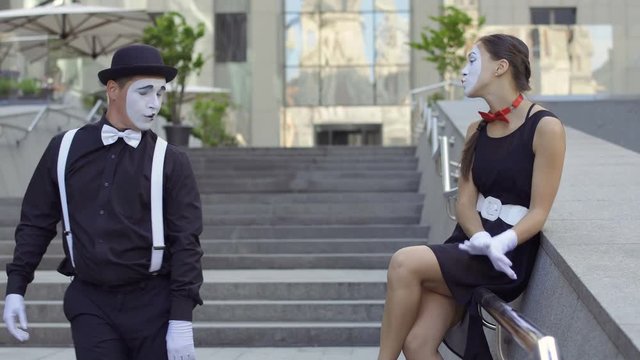 Handsome guy mime in hat give invisible bouquet of flowers to young cute girl