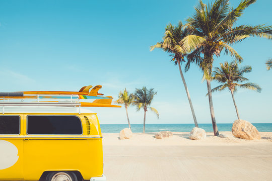 vintage car parked on the tropical beach (seaside) with a surfboard on the roof - Leisure trip in the summer. retro color effect