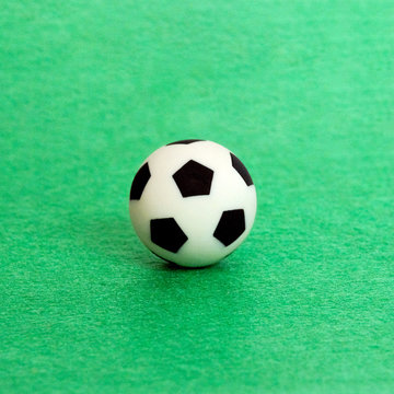 Souvenir soccer ball on a green felt background. Shallow depth of field. A square picture.