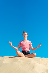 ein junges Mädchen macht Yoga Übungen  / Meditation in freier Natur, vor blauem Himmel