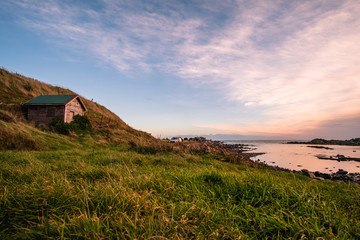Fototapeta premium Beautiful scene of a landscape in a rural area beside the ocean at sunset. Cosy Nook, New Zealand.