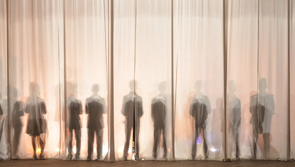 the silhouette of the men behind the curtain in the theater on stage, the shadow behind the scenes...