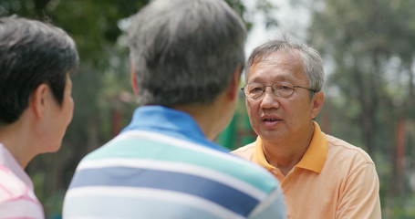 Senior friends chatting together at outdoor park