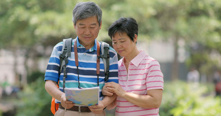 Asian old couple go travel and look at the map together at outdoor