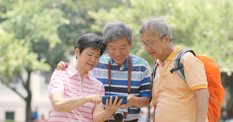 Senior old friends go travel together with backpack, cellphone and camera