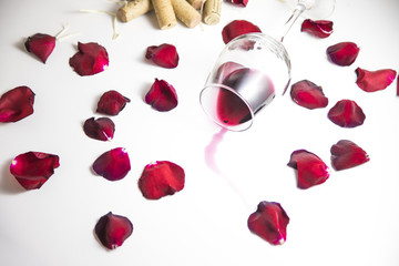 Fototapeta na wymiar Glass of wine on the table with rose petals