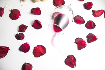 Glass of wine on the table with rose petals