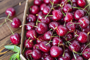 Red ripe cherries, red cherries on wooden table, brown wooden background, top view