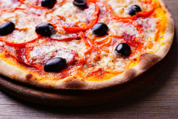 Delicious pizza with salami and black olives on wood, close up. Italian food, restaurant menu photo