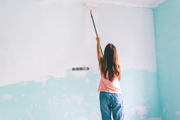 Child painting a wall in room