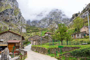 Street with old typical houses in a cloudy spring day, Cain de Valdeon, Picos de Europa,  Castile and Leon, Spain. Cain is a village in the mountains, whose have starting points of many hiking trails.
