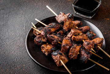 Grilled beef liver on skewers, with teriyaki or soy sauce, yakitori, dark rusty  table copy space...