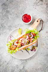 Assortment of different homemade Vegan Carrot Hot Dogs, with fried onion, avocado, chili, mushrooms, tomatoes and beans, grey stone background copy space top view