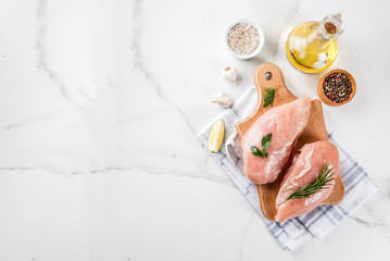 Raw meat, chicken breast filet, with olive oil, herbs and spices on white marble background, copy space top view