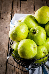 Fresh raw organic farm green apples in black metal basket, old rustic wooden background, copy space