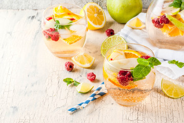 Summer cold cocktail, fruit and berry white sangria with apple, lemon, oranges and raspberry. light concrete background, copy space
