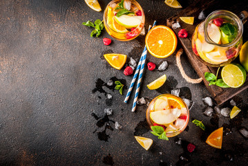 Summer cold cocktail, fruit and berry white sangria with apple, lemon, oranges and raspberry. dark background, copy space top view