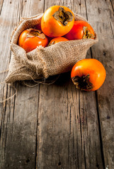 Delicious raw ripe persimmon fruit on old wooden background copy space