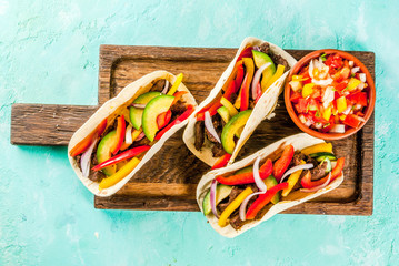 Homemade Mexican pork tacos with vegetables and salsa, on light blue background copy space top view