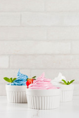 Healthy diet summer dessert, vanilla and berry frozen yogurt or  soft ice cream in white bowls, white marble background copy space