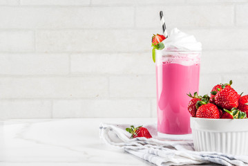 Cold strawberry  milkshake with fresh berries and mint on white marble background copy space