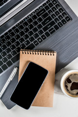 Workplace, white desk table with laptop, smartphone, coffee cup and notepad, Top view with copy space