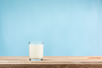 a glass of milk on wooden table on blue background