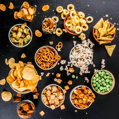 Variation different unhealthy snacks crackers, sweet salted popcorn, tortillas, nuts, straws, bretsels, back chalkboard copy space
