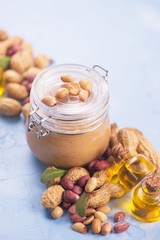 Natural peanut butter with oil in a glass jar and peanuts
