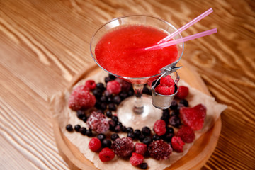 Refreshing cocktail with raspberries and alcohol, red. Decorated with fresh forest berries.