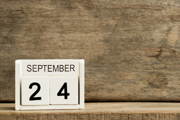 White block calendar present date 24 and month September on wood background