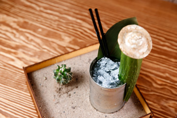 Refreshing cocktail with tequila cucumber, cactus and ice. Original feed in box with sand, leaf of...