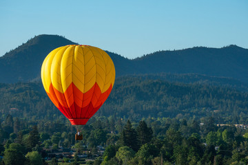 Hot air balloon in front of wooded hills
