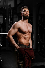 Fototapeta na wymiar Man is standing in gym with inflated body, muscles of press are strained, vertical photo. Bodybuilding fitness concept.