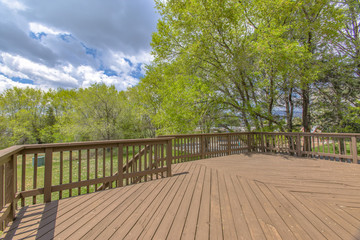 Wooden deck with cloudy skies and green trees