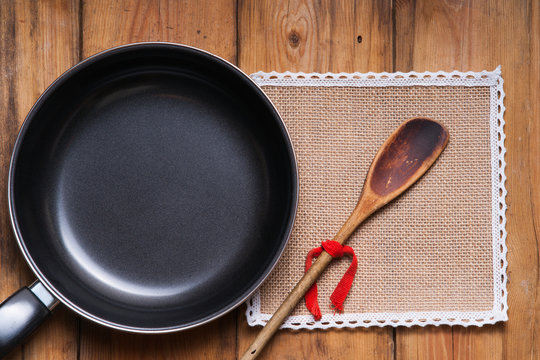 Frying pan, wooden spoon and tablecloth on the table background 