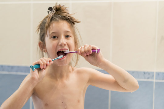 Little girl brushes teeth with two brushes. Stomatology. oral health care.