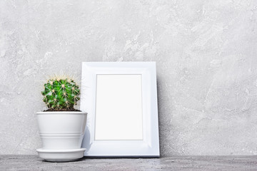 Small cactus in flower pot and mock-up of white frame with copy space for poster