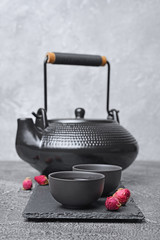 Asian black traditional teapot and teacups with healthy herbal rose tea