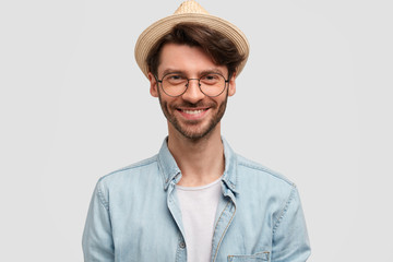 Pleased good looking male in stylish straw hat, expresses confidence and positive emotions, has...