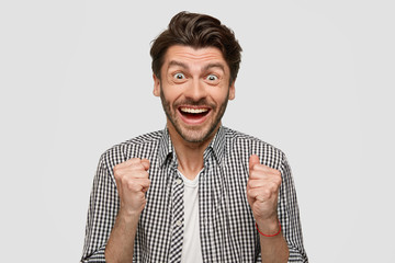 Joyful businessman clenches fists, happy to win shareholding, celebrates his success, expresses...
