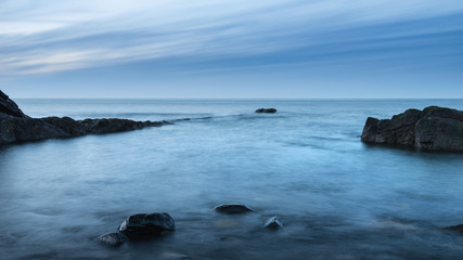 Beautiful long exposure landscape image of beach at Dunstanburgh in Northumberland England