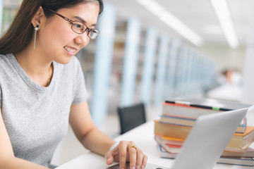 Asian Woman using laptop in the library.