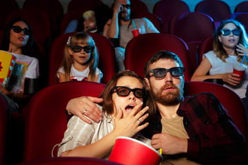 Obraz premium friends sitting in cinema watch film eating popcorn and drinking water.